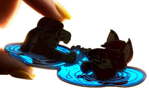 A disney pin inspired by the fox and the hound. this pin includes the fox and the hound playing together in water. the water is transparent and this image is backlit to highlight this.