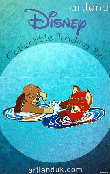 A disney pin inspired by the fox and the hound on a turquoise backing card. this pin includes the fox and the hound playing together in water. the water is transparent.